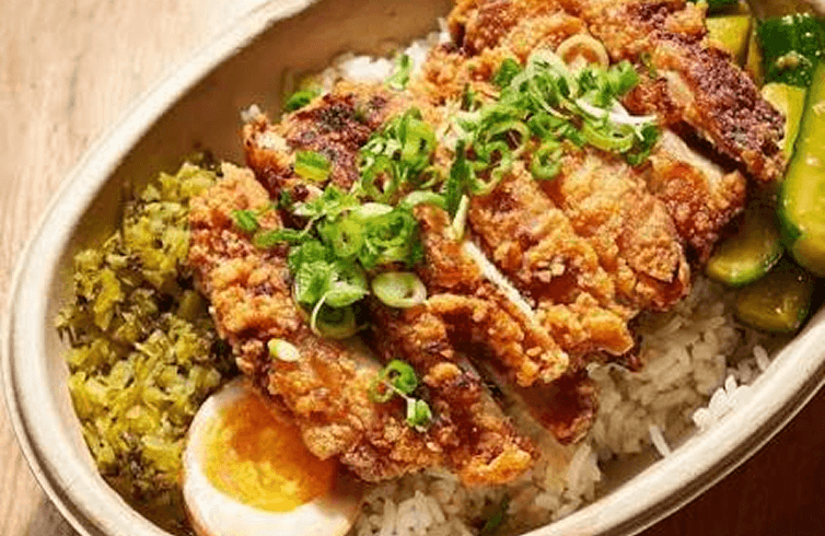 An open bian dang box: fried pork cutlet and scallions over rice, with pickled greens, cucumber and a soy egg.