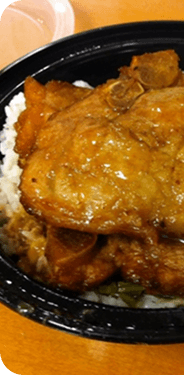 A takeaway box of braised pork and rice, lid off.